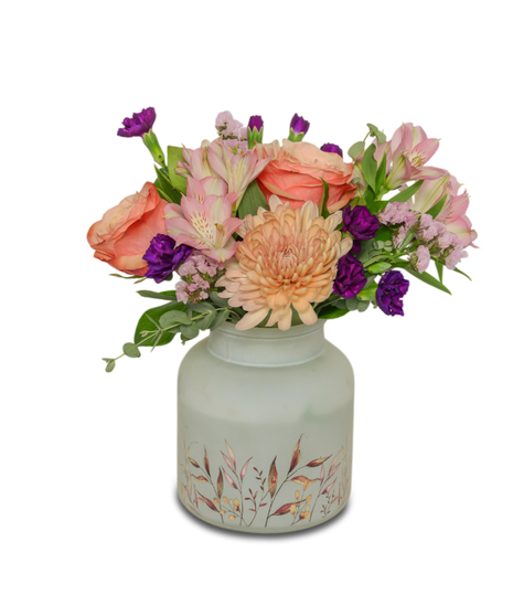 Frosted vase with botanical print filled with peach, pink and purple flowers.