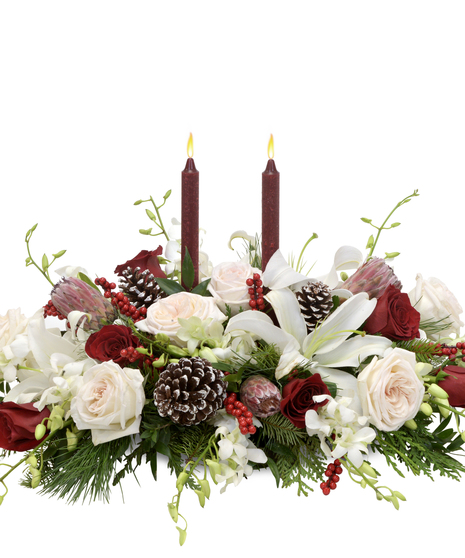 Luxurious centerpiece with garden roses, mink proteas, white lilies, Italian ruscus, pine, berries, frosted pinecones, and candles. A festive sensory delight.