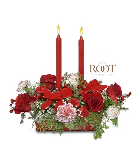 Red and white Christmas centerpiece with roses, peppermint carnations, evergreens, berries, velvet ribbons, and Root Candles in a white rectangular container.