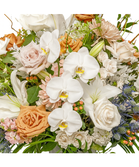 Ascent floral arrangement with neutral roses, white lilies, hydrangea, chrysanthemums, eryngium, curly willow, and greenery in a glass vase