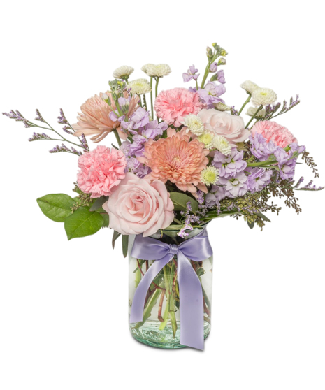 Amelia is a pastel bouquet with pink roses, lavender stock, Linette mums, and carnations in a clear jar tied with a lavender ribbon. Ideal for Mother's Day and more.