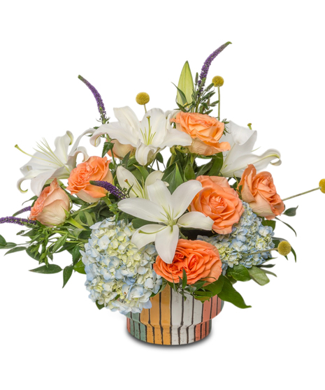 Modern Muse is a floral arrangement with white lilies, peach roses, and blue hydrangea in a striped ceramic vase. A bold, artistic design offered in two sizes.