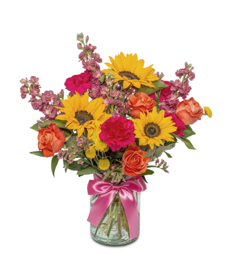 Sunny Side is a bright bouquet of sunflowers, roses, carnations, and more in a clear jar with a hot pink bow. A cheerful, uplifting gift full of color and joy.